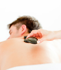 Fototapeta premium Close-up of a positive young man having a back massage with hot
