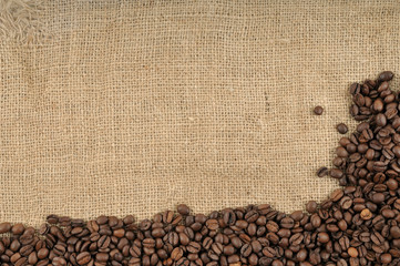 Coffee beans on  jute background with a big space.