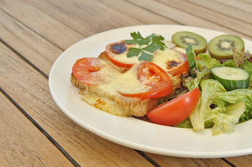 Fototapeta na wymiar Käsetoast mit salat und Früchten Kiwi und Tomate