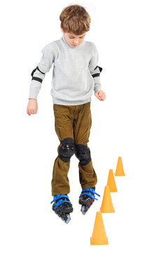 little boy rollerblading near orange cones looking down isolated