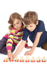 Naklejka premium boy and girl playing with wooden railway sitting on floor