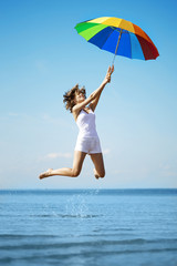Girl jump  with a rainbow umbrella
