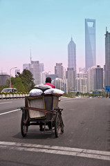 Homme en tricycle de cargaison, vélo cargo chargé, tours modernes en arrière plan à Shanghai - Chine