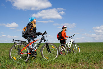 Two girls on bicycles in the countryside.
