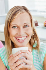 Glowing woman holding a cup of coffee at home