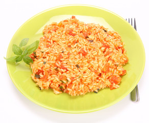 Risotto with tomatoes on a green plate decorated with basil