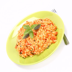 Risotto with tomatoes on a green plate decorated with basil