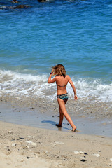 Fototapeta na wymiar jeune fille en maillot de bains marchant sur la plage