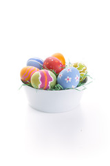 An isolated white bowl with a bunch of rough painted easter eggs