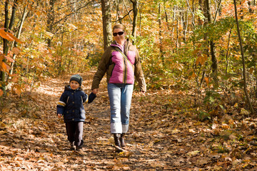 Mother and son taking a walk in autumn forest