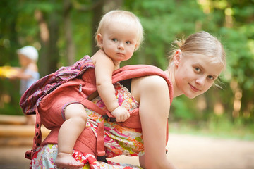mother carrying daughter looking into forest
