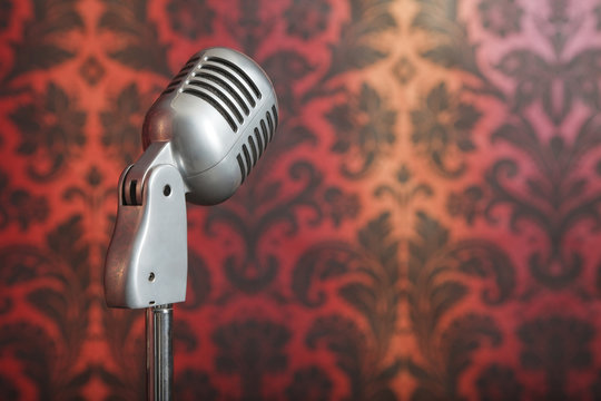 vintage microphone on stand photographed against wallpaper