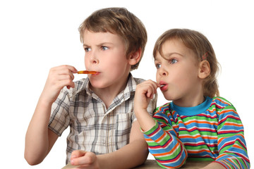 little boy and girl eating lollipops and looking at left side