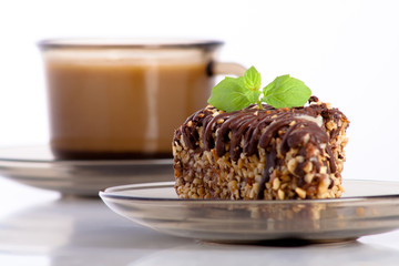 chocolate cake with nuts decorated with mint and a cup of coffee