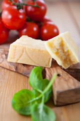 Grana padano cheese,tomatoes and basil on cutting board