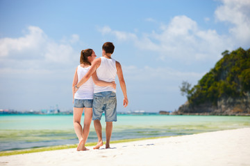 Romantic couple walking along tropical beach