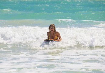 teenage girl boogie boarding the waves in Hawaii.