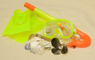 A child's snorkel, mask and flippers laying on the sand