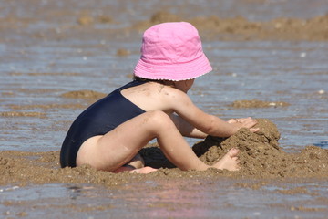 Petite fille jouant dans le sable à marée basse