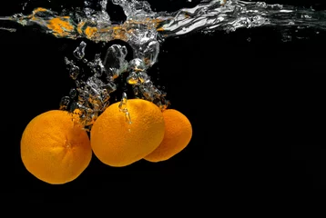  Verse mandarijnen vallen in water met bubbels op zwart © artjazz