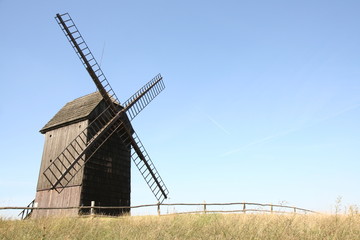 Fototapeta na wymiar Old windmill (trestle type) in a field with a fence