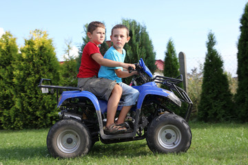 Two young boys driving a quad bike