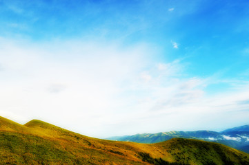 Cloudy blue sky upon green mountain ridge