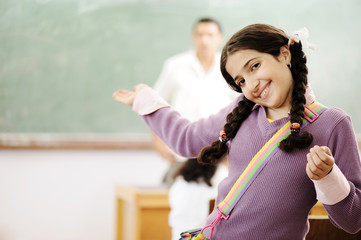 Welcome to my school: adorable schoolgirl smiling in classroom