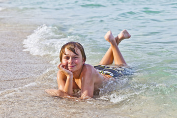 boy enjoys lying at the beach in the surf