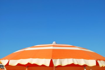 Orange striped beach umbrella on blue sky, Rimini, Italy - Powered by Adobe