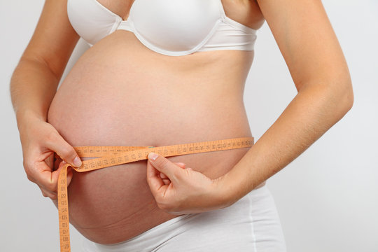 Schwangere Frau misst ihren Bauchumfang