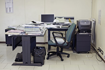 Lonely office room with messy desk filled up with documents
