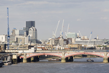 Thames river and cranes in front of modern buildings London UK