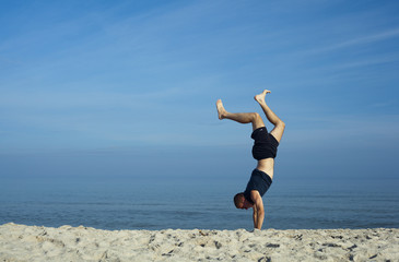 Obraz premium Młody mężczyzna gimnastykujący się na plaży