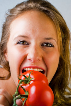 Frau beisst lustvoll in eine Tomate