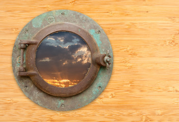 Antique Porthole with View of Sunset on Bamboo Wall