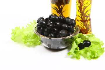 A bottle of olive oil with herbs and black olives
