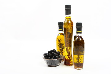 A bottle of olive oil with herbs and black olives