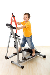 Fototapeta na wymiar Smiling boy on elliptical trainer in the gym