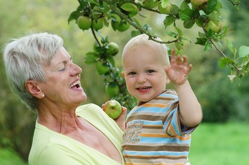 Grandmother with child under apple tree