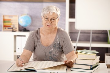 Senior teacher in school searching in a book