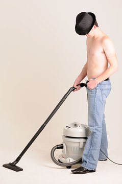 young man doing work at home with a vacuum cleaner
