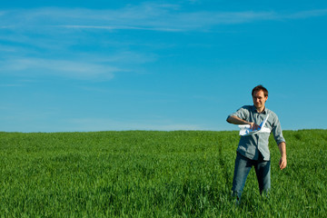 Naklejka na ściany i meble young man throwing a paper in the green field