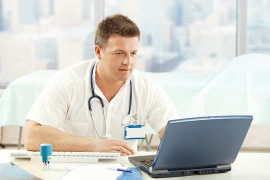 Mid-adult physician working with laptop