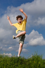 Boy jumping, running against blue sky