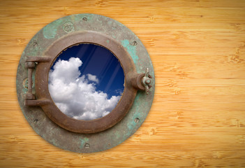 Antique Porthole on Bamboo Wall with View of Blue Sky and Clouds