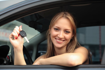 Obraz na płótnie Canvas The happy woman showing the key of her new car