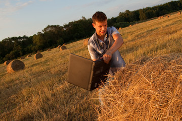 Naklejka na ściany i meble The young man in the field with the computer