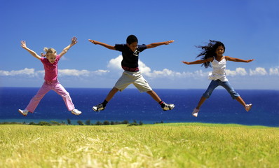 Fototapeta na wymiar Trio d'enfants sautant dans l'herbe.