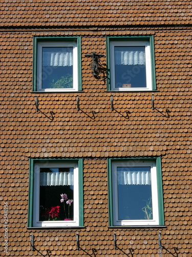 "Hausfassade mit rotbraunen Schindeln und vier Fenstern" Stockfotos und